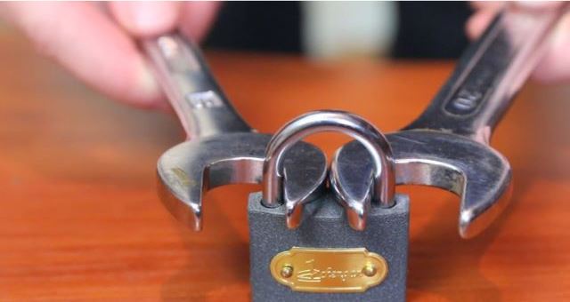 A person Breaking a Lock With two wrenches