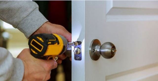A person drilling a bedroom door lock