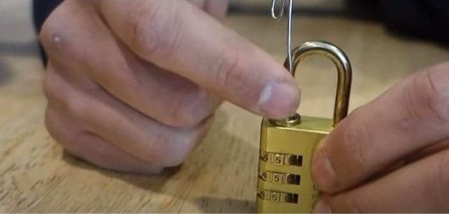 A person cracking A Combination Lock With A Paperclip