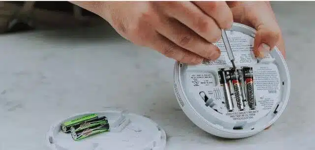 A person Removing Smoke Alarm Battery